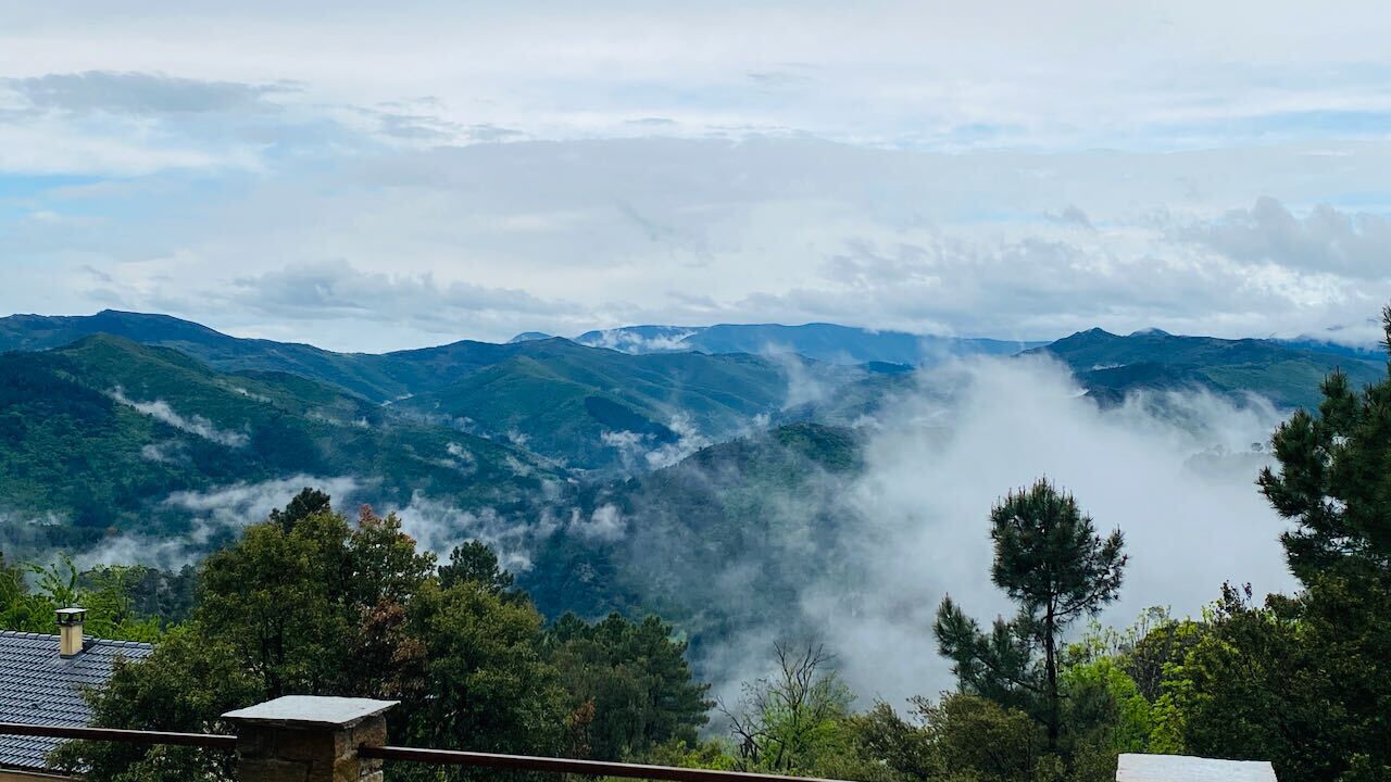 A mountainous landscape with a house in the foreground and a view of the valley below.