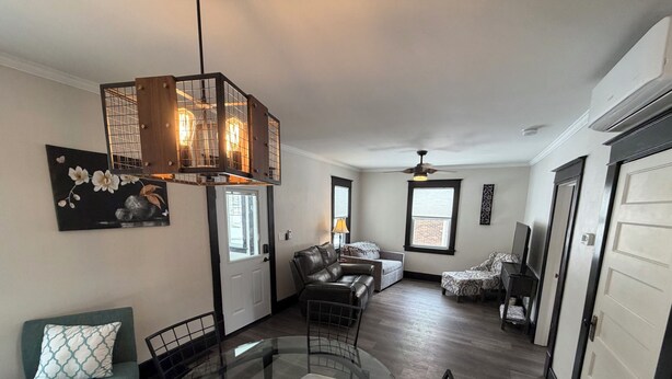 A spacious living room with a glass dining table, leather sofas, and a modern chandelier.