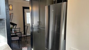A modern kitchen with stainless steel appliances, a dining area with a table and chairs, and a wooden floor.
