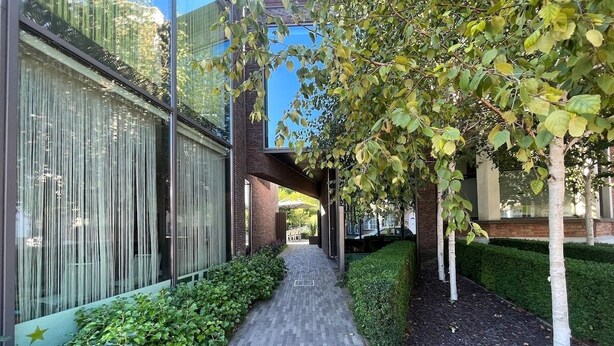 Ein Weg, gesäumt von Grünflächen und moderner Architektur, der zu einem Gebäude mit Glasfassade führt.