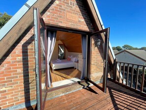 A bedroom with a wooden floor, a bed, and a window with curtains.