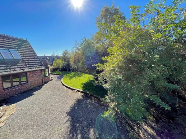 A residential property with a paved driveway, a brick house with a sloped roof, and a well-maintained lawn.
