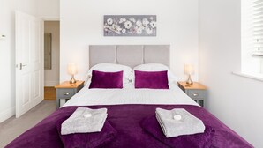 Een slaapkamer met een bed, twee nachtkastjes, een raam met zonwering en een deur.