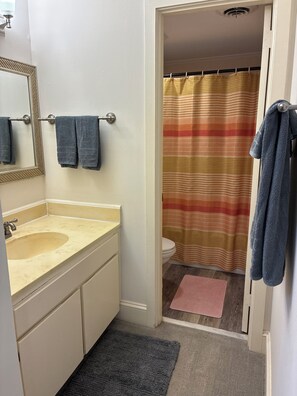 A bathroom with a sink, mirror, towel rack, and a shower curtain. - Cozy 2-bedroom condo with sunroom on a beautiful golf course St. Simons Island.
 (St. Simons Island)