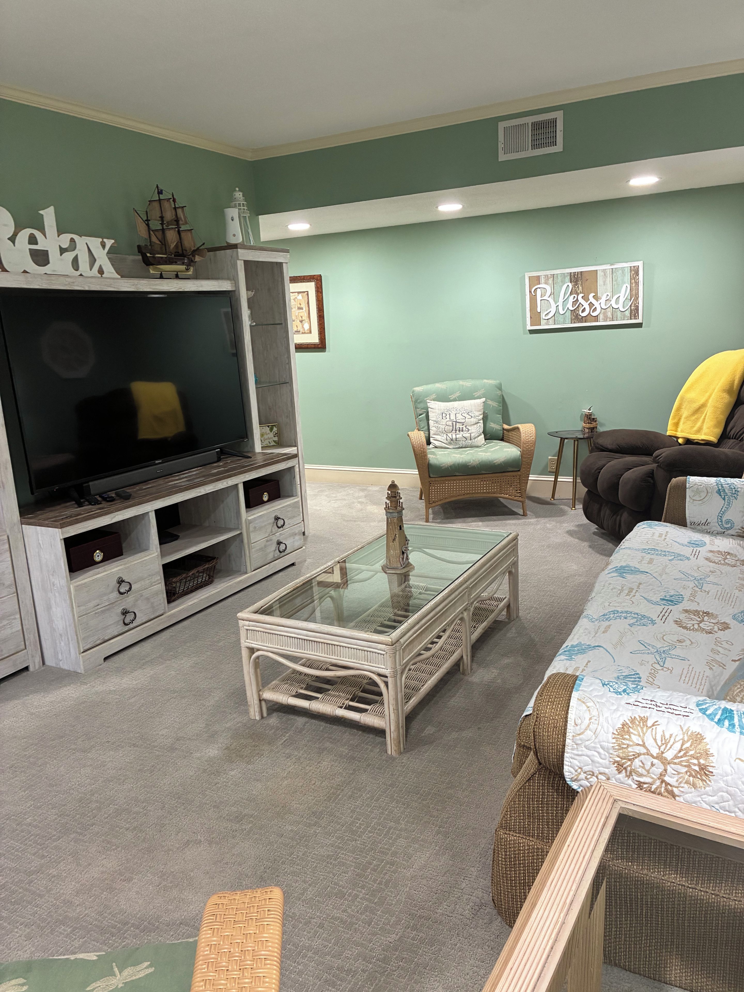 A living room with a television, wicker furniture, and a green wall.