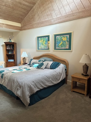 Ein Schlafzimmer mit einem Bett, einem Nachttisch, einer Lampe, einem Bücherregal und zwei gerahmten Bildern an der Wand.