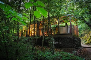 Eine Holzhütte mit Glaseinfassung, umgeben von dichtem Wald.