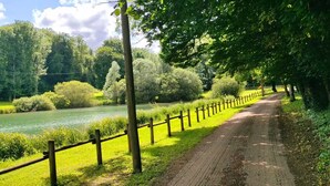 A dirt path alongside a river with a wooden fence and lush greenery. - L'Ange De Fer (immersion totale en pleine forêt) (Illoud)