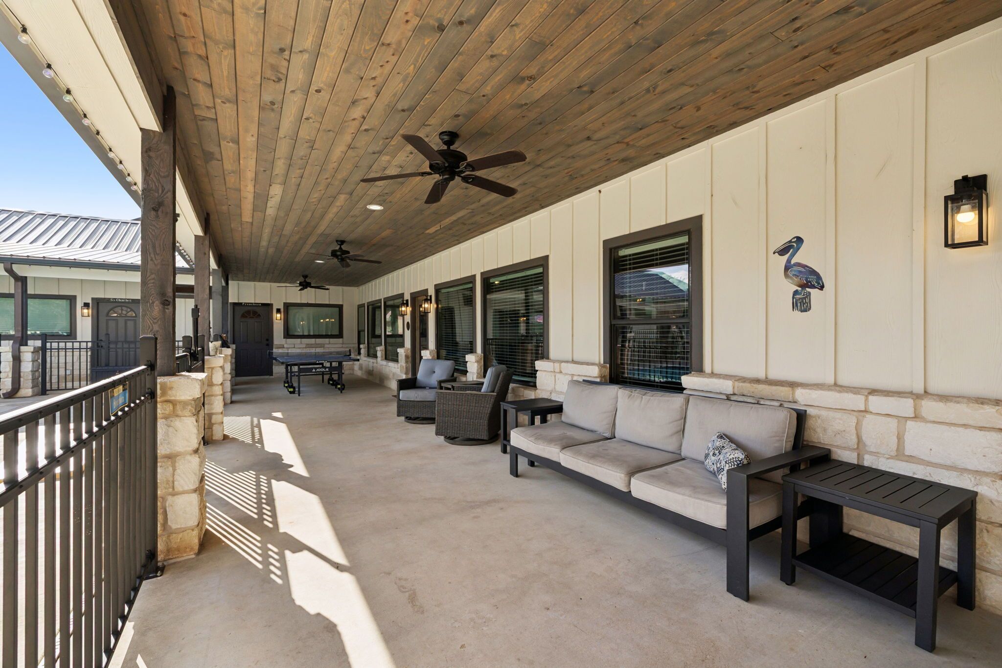 An outdoor covered patio area with seating, ceiling fans, and a view of the building's exterior.