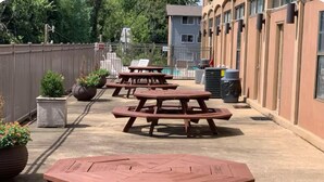 Un espacio al aire libre con varias mesas de picnic de madera y plantas en macetas.