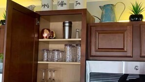 Una cocina con armarios de madera, un refrigerador de acero inoxidable y frascos de vidrio en los estantes.