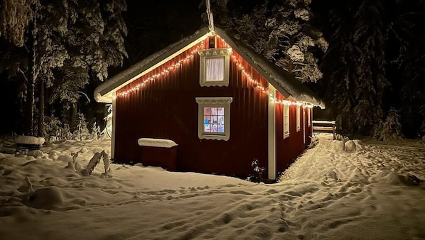 A snow-covered cabin with a red exterior and a small porch, surrounded by trees. - Cozy 6-person house in the middle of the forest, enjoy the space and 
the peace
 (Klässbol)