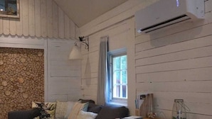 A cozy living room with a sofa, a dining table, and a wooden wall. - Cozy 6-person house in the middle of the forest, enjoy the space and 
the peace
 (Klässbol)