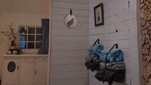 A room with a wooden wall, a mirror, and a rack with folded towels. - Cozy 6-person house in the middle of the forest, enjoy the space and 
the peace
 (Klässbol)