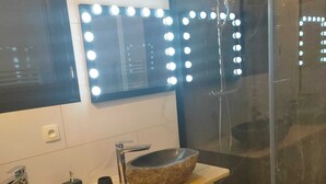 Une salle de bain avec deux lavabos, un miroir avec éclairage intégré, une douche et un porte-serviettes.