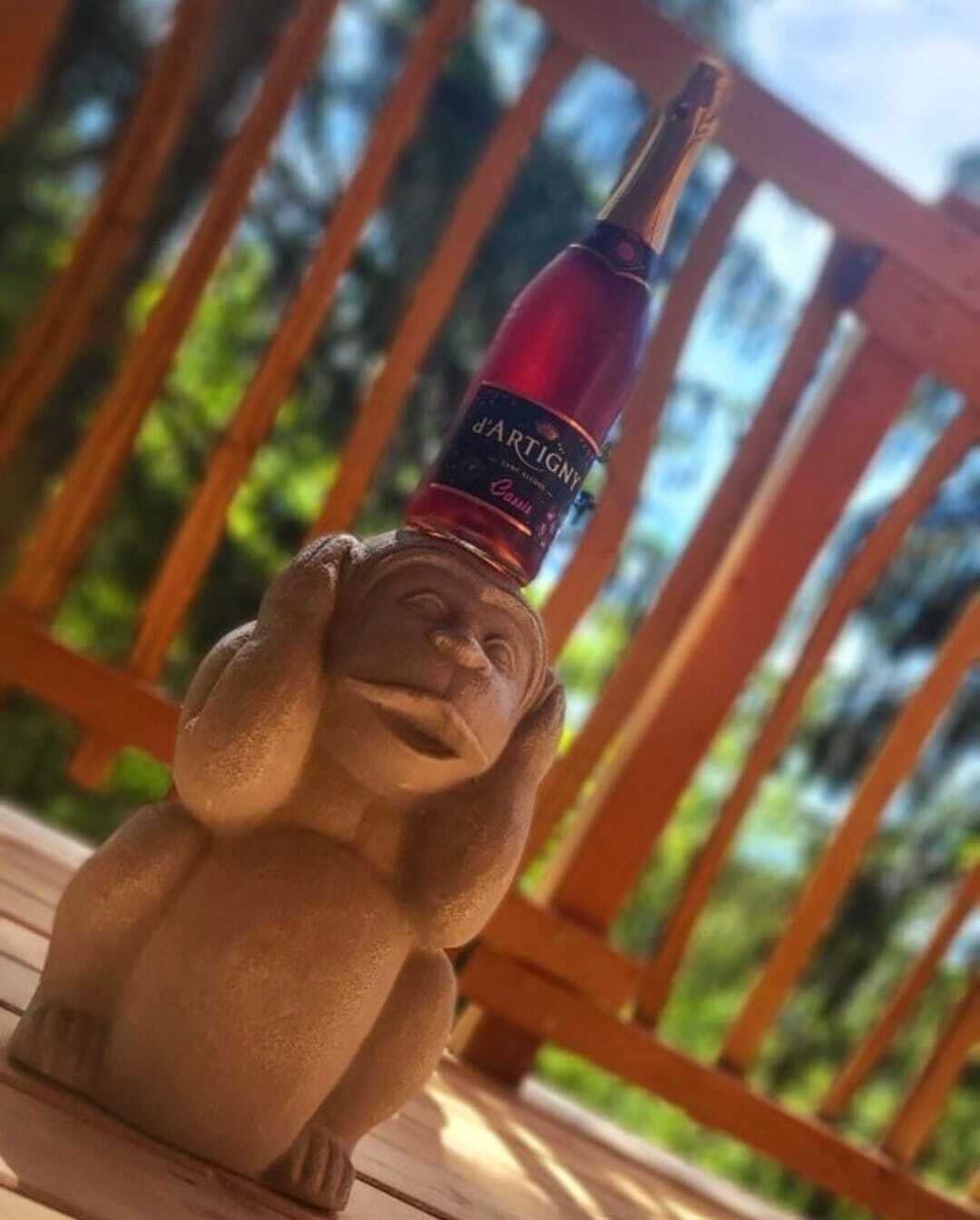 A wooden deck with a statue of a monkey holding a bottle of wine.