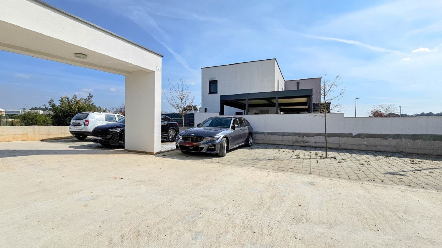 A modern building with a flat roof and a covered parking area.