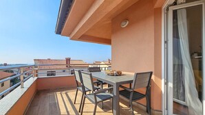 Een balkon met een tafel, stoelen, een schuifdeur en uitzicht op andere gebouwen.