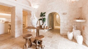 Ein rustikales Interieur mit freiliegenden Steinwänden, Holzbalken und einem zentralen Tisch mit Hockern.