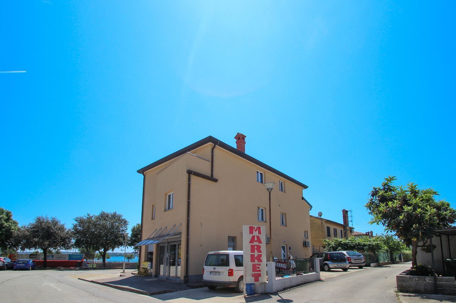 A two-story building with a beige facade, a visible entrance, and a sign that reads "MARKET".