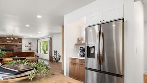 A modern kitchen with a stainless steel refrigerator, wooden dining table, and a brick wall.