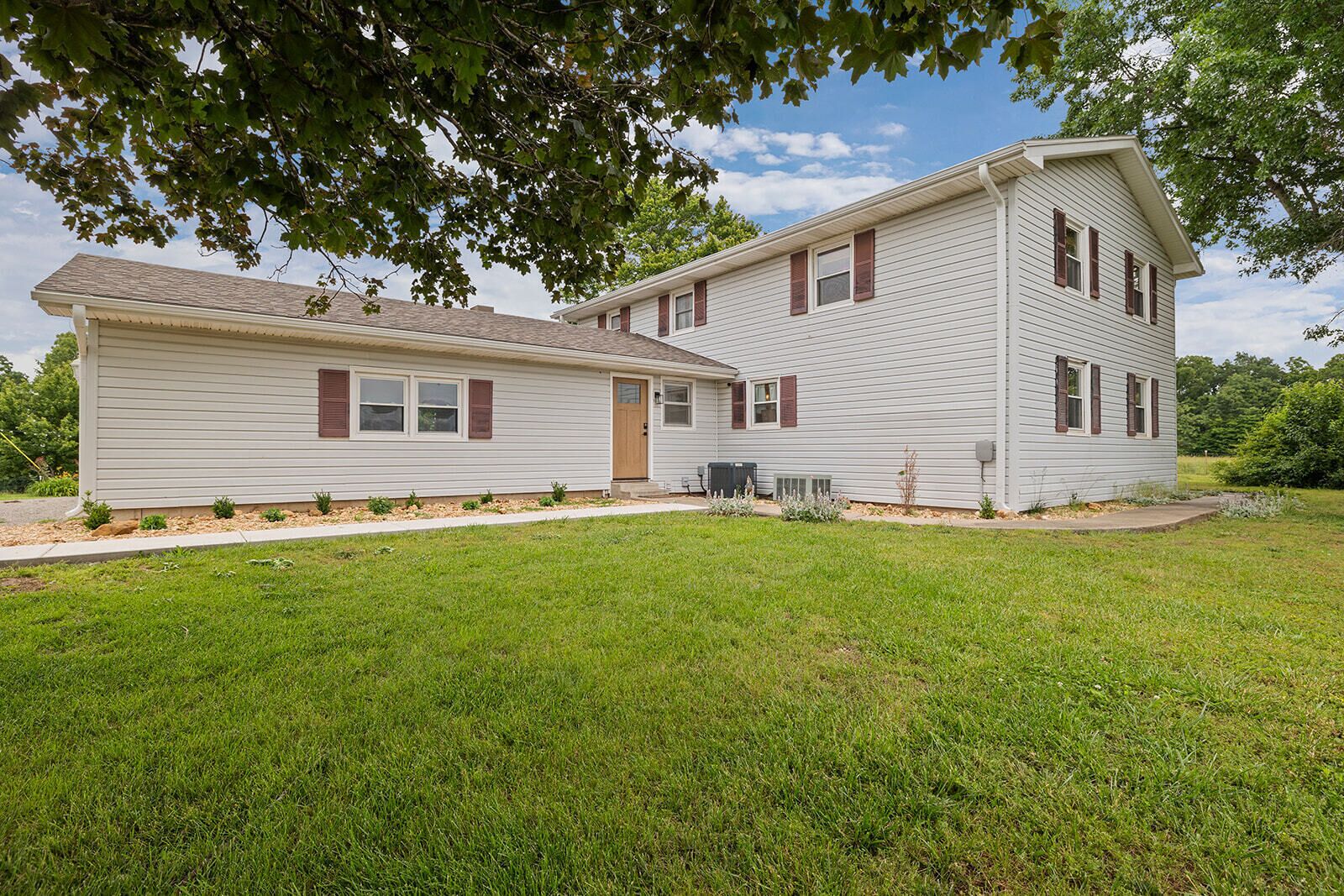 A two-story house with a front porch, a small attached garage, and a well-maintained lawn.