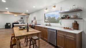 A modern kitchen with wooden cabinets, a central island, a dishwasher, and a window with a view.