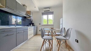 A modern kitchen with grey cabinets, a black countertop, and a window providing natural light. - Apartment Vili (Novigrad)