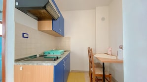 Une cuisine compacte équipée d’une cuisinière intégrée, d’un évier et d’une petite table à manger avec une chaise.