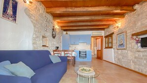 A cozy living room with a blue sofa, a small glass table, and a kitchen in the background. - Breathtaking sea views and only 30 metres to the beach (Novigrad)