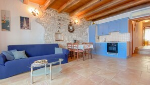 A living room with a blue sofa, a glass coffee table, and a stone wall with a clock. - Breathtaking sea views and only 30 metres to the beach (Novigrad)