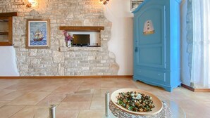 A room with a stone wall, a fireplace, a blue cabinet, and a glass table with a decorative plate. - Breathtaking sea views and only 30 metres to the beach (Novigrad)