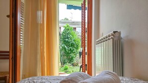 Una cama con toallas enrolladas y vistas a un jardín a través de una puerta abierta.