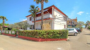 Un edificio de dos pisos con fachada roja y blanca, un balcón y un techo de tejas rojas.