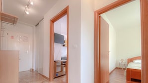 A spacious room with a large bed, a small bedside table, and a nightstand. There is a wooden door leading to another room.