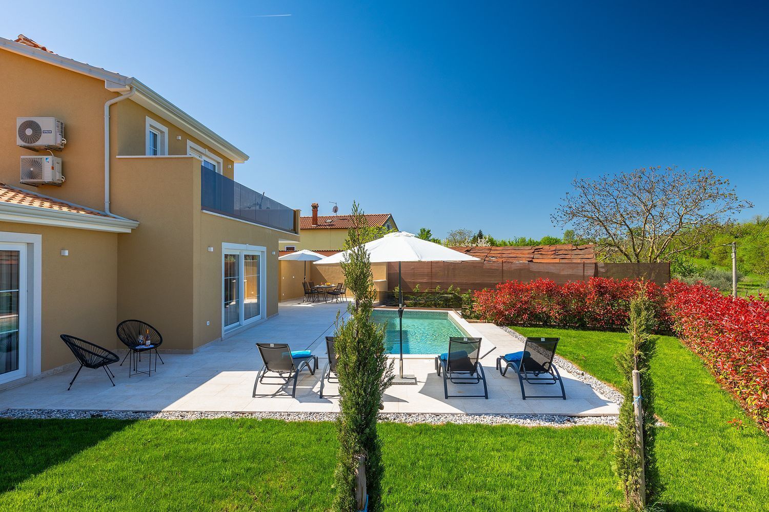 A house with a swimming pool, outdoor seating, and a well-maintained garden.