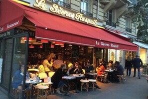 Un espace extérieur aménagé avec des tables et des chaises, où l’on peut s’asseoir au restaurant Le Sévres Raspail.
