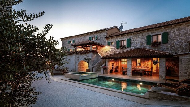 Une villa en pierre dotée d’une piscine, d’un espace salon extérieur et d’un patio couvert.