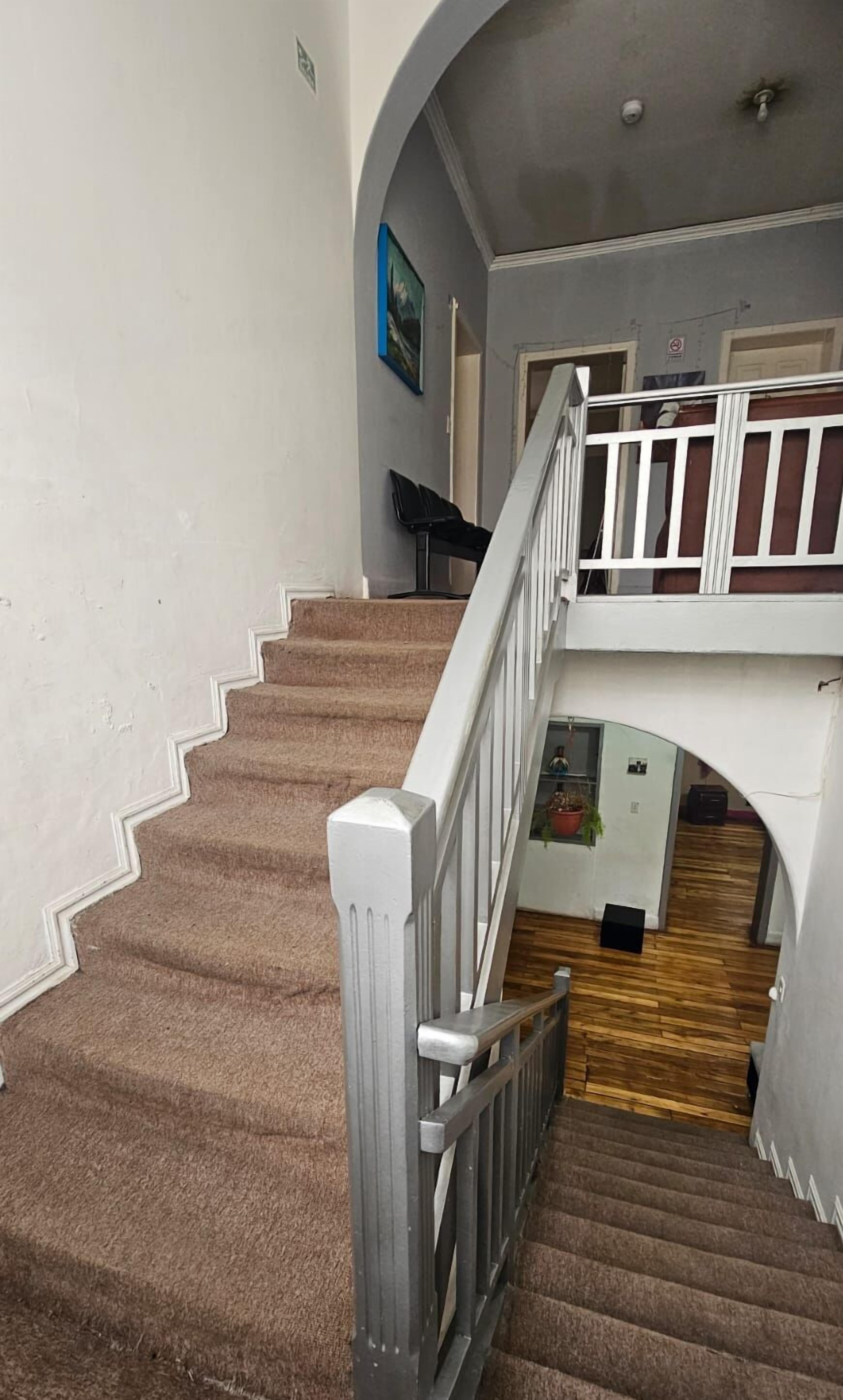 Een trap met een witte leuning en beklede treden die naar een hoger niveau leiden.