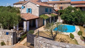 A stone villa with a swimming pool, a covered patio, and a fenced garden. - Mediterranean stone house with private pool, sauna, sea view, summer kitchen (Sveti Lovrec)