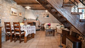 A rustic dining area with a stone wall, wooden chairs, a lace tablecloth, and a wooden staircase. - Mediterranean stone house with private pool, sauna, sea view, summer kitchen (Sveti Lovrec)