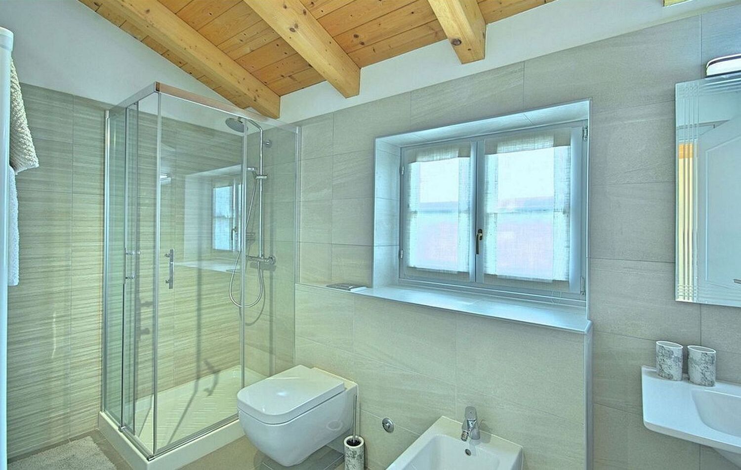Une salle de bain moderne avec une douche à parois de verre, des toilettes, un lavabo et une fenêtre située au-dessus du lavabo.