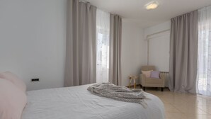 Een slaapkamer met een bed, een stoel en een klein tafeltje.