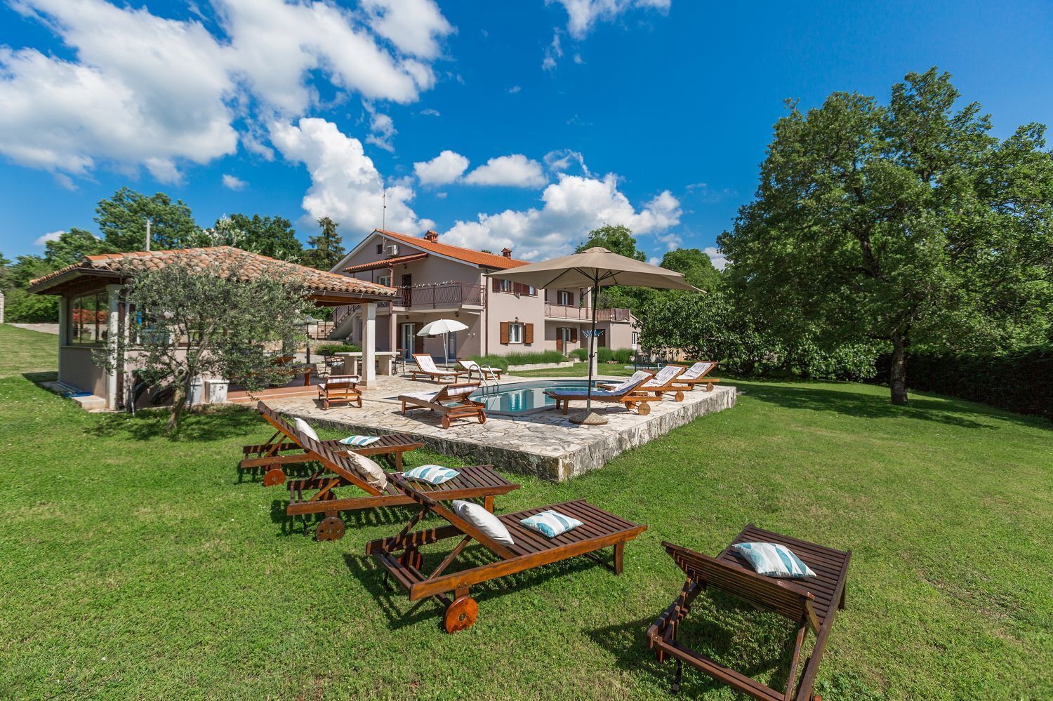 Una casa de dos pisos con piscina, mobiliario exterior y jardín.