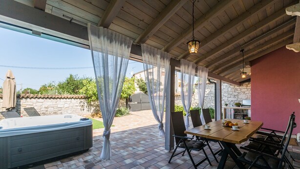 Une terrasse extérieure avec un jacuzzi, une table à manger et des chaises.