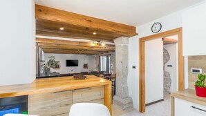 Une cuisine moderne avec des poutres en bois, un îlot central et un mur en pierre.
