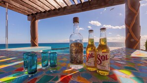 A table with three bottles and four glasses, set against a view of the ocean.
