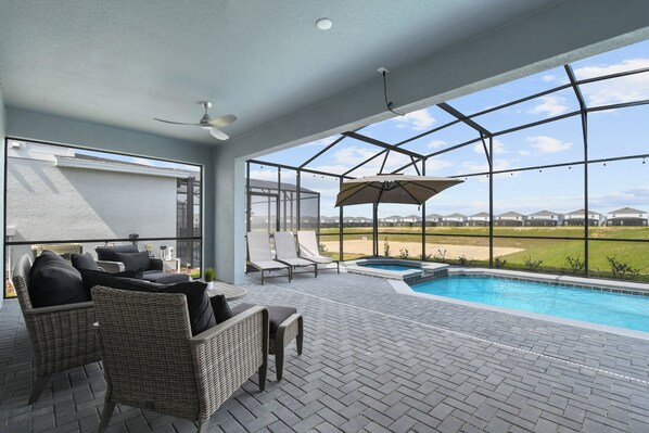 Un patio exterior con mobiliario de mimbre, una piscina y vistas a un campo de golf.