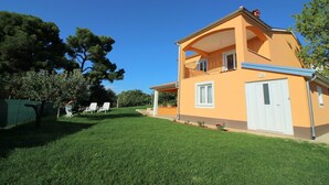 A two-story house with a balcony, a garage, and a well-maintained lawn.