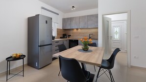 A modern kitchen with a built-in refrigerator, a dining table with chairs, and a vase of flowers.